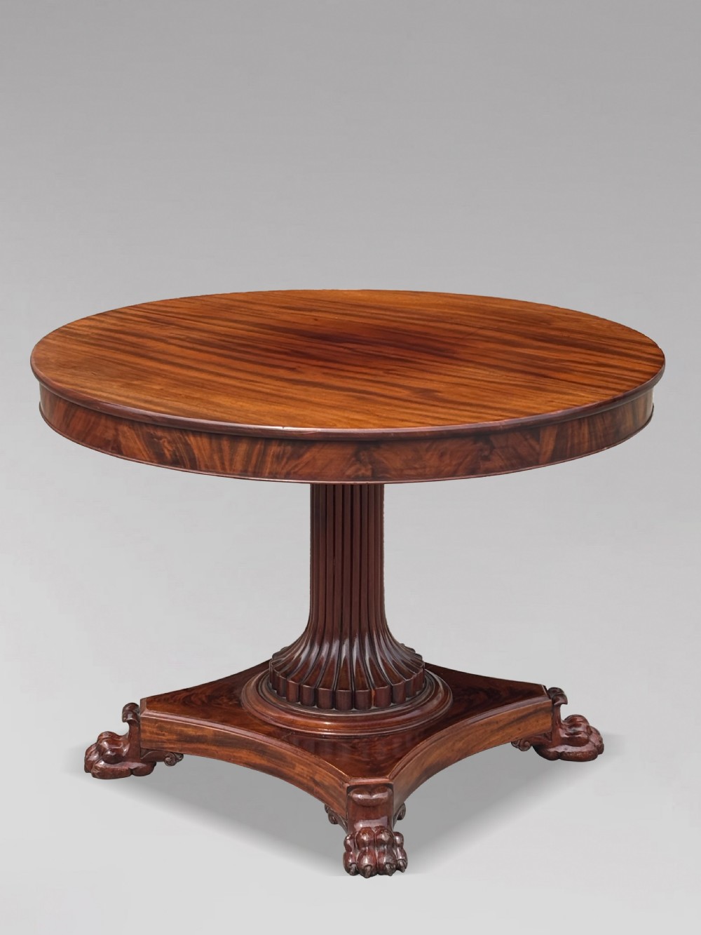 A 19th-century French Charles X mahogany centre table with a circular top, fluted central pedestal, and quadform base on carved feet.