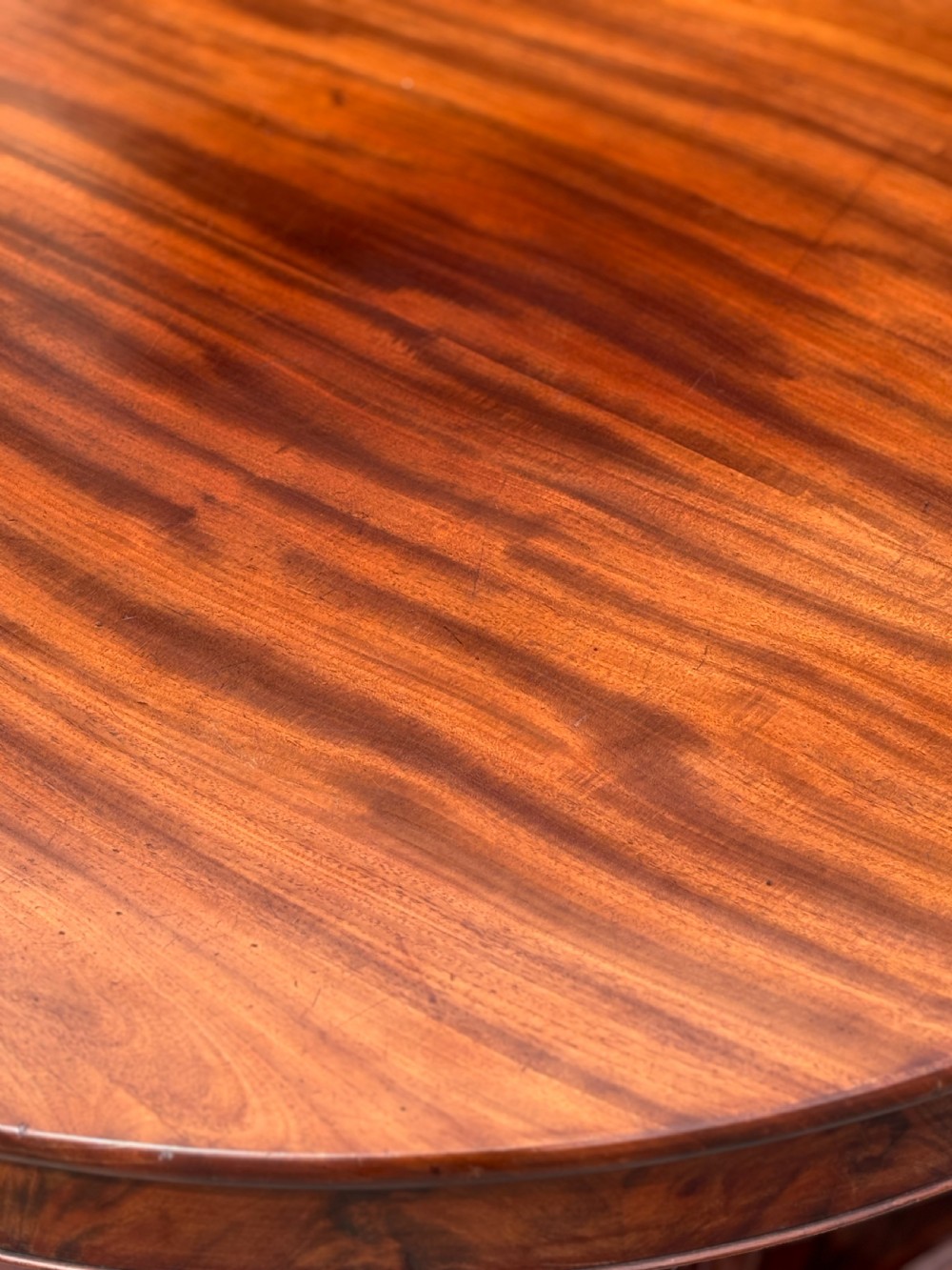A 19th-century French Charles X mahogany centre table with a circular top, fluted central pedestal, and quadform base on carved feet. View VII