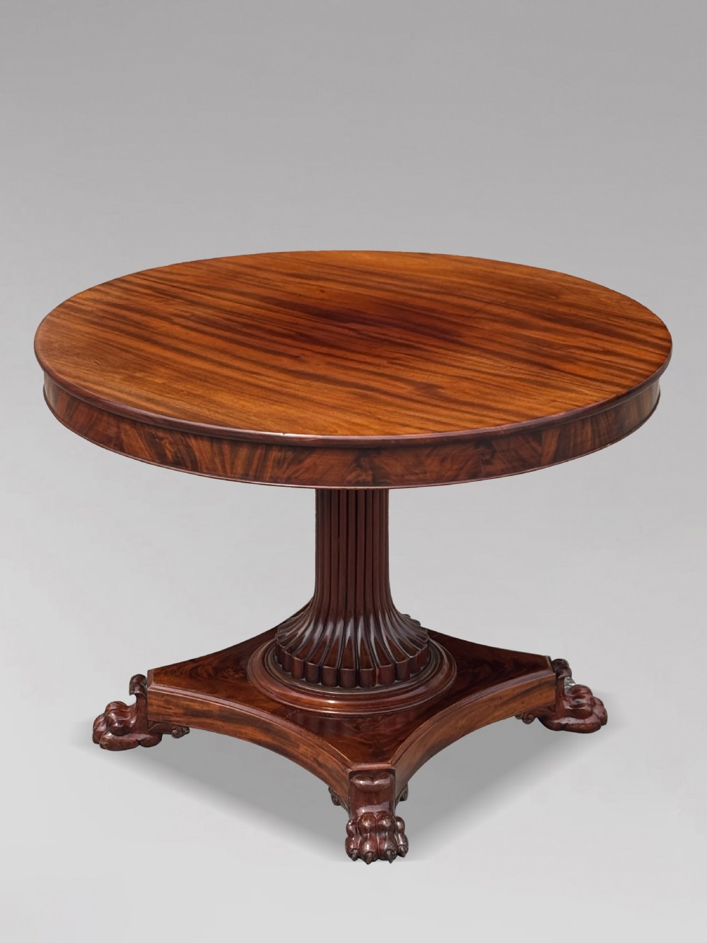 A 19th-century French Charles X mahogany centre table with a circular top, fluted central pedestal, and quadform base on carved feet. View VIII