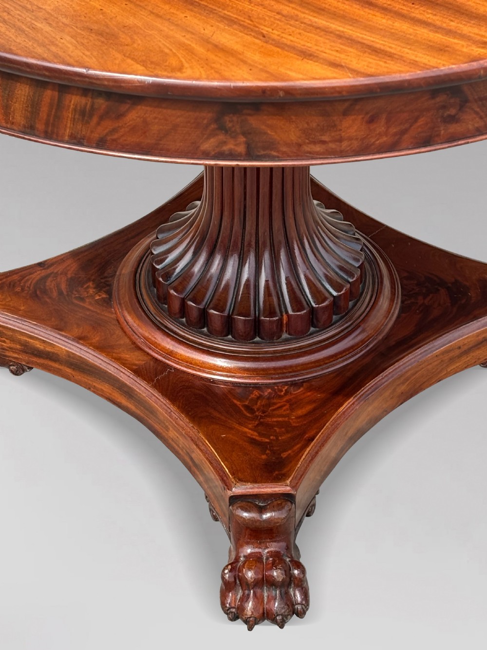 A 19th-century French Charles X mahogany centre table with a circular top, fluted central pedestal, and quadform base on carved feet. View X
