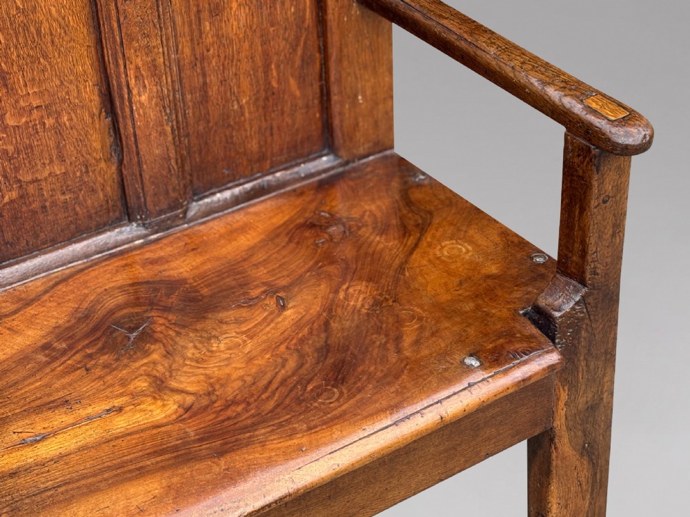 An 18th-century Georgian high-back settle crafted from oak and elm featuring a panelled back and wooden armrests. View III