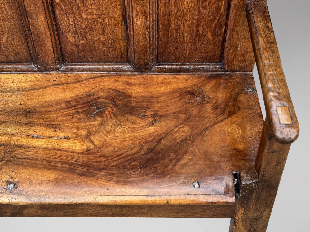 An 18th-century Georgian high-back settle crafted from oak and elm featuring a panelled back and wooden armrests. View VIII