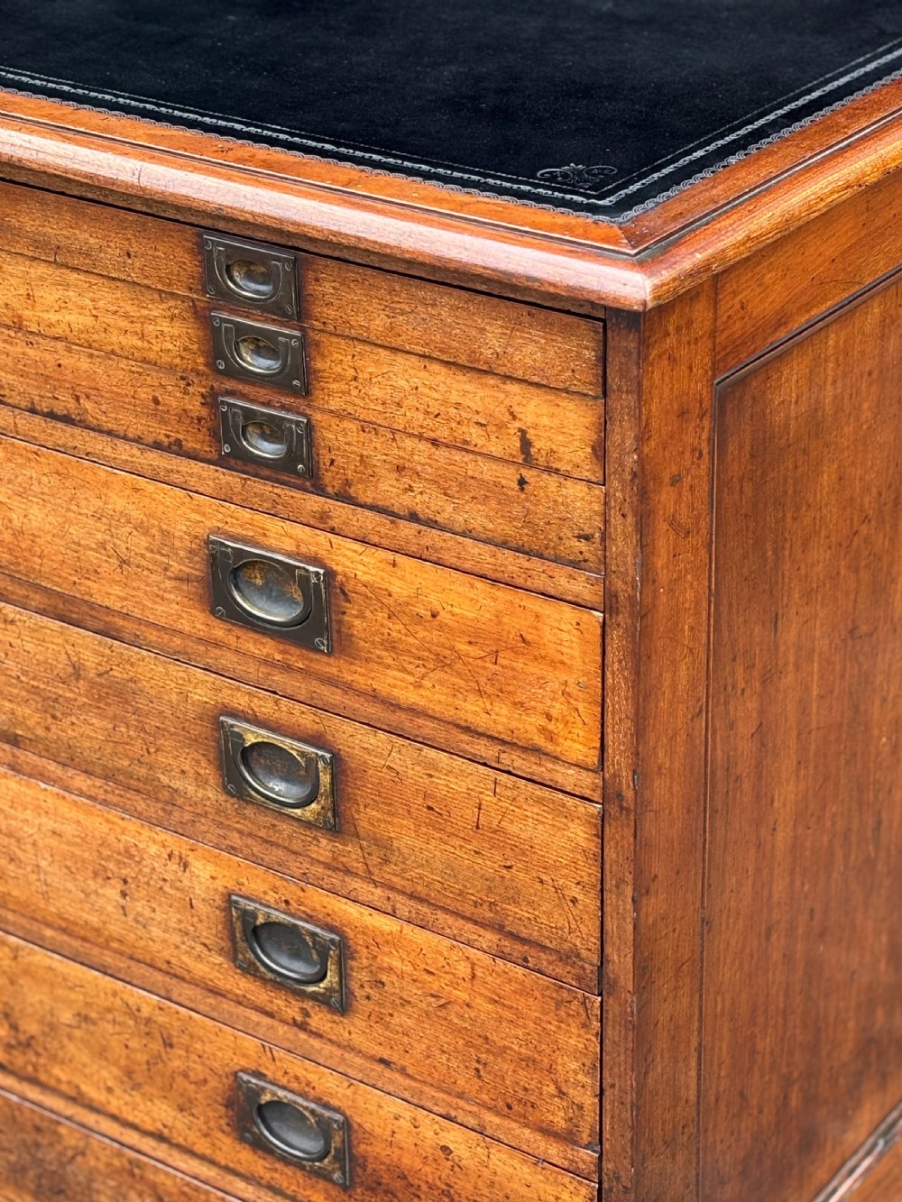 A nineteenth-century mahogany campaign filing cabinet featuring multiple drawers with flush brass handles and a dark leather inset top surface. View V