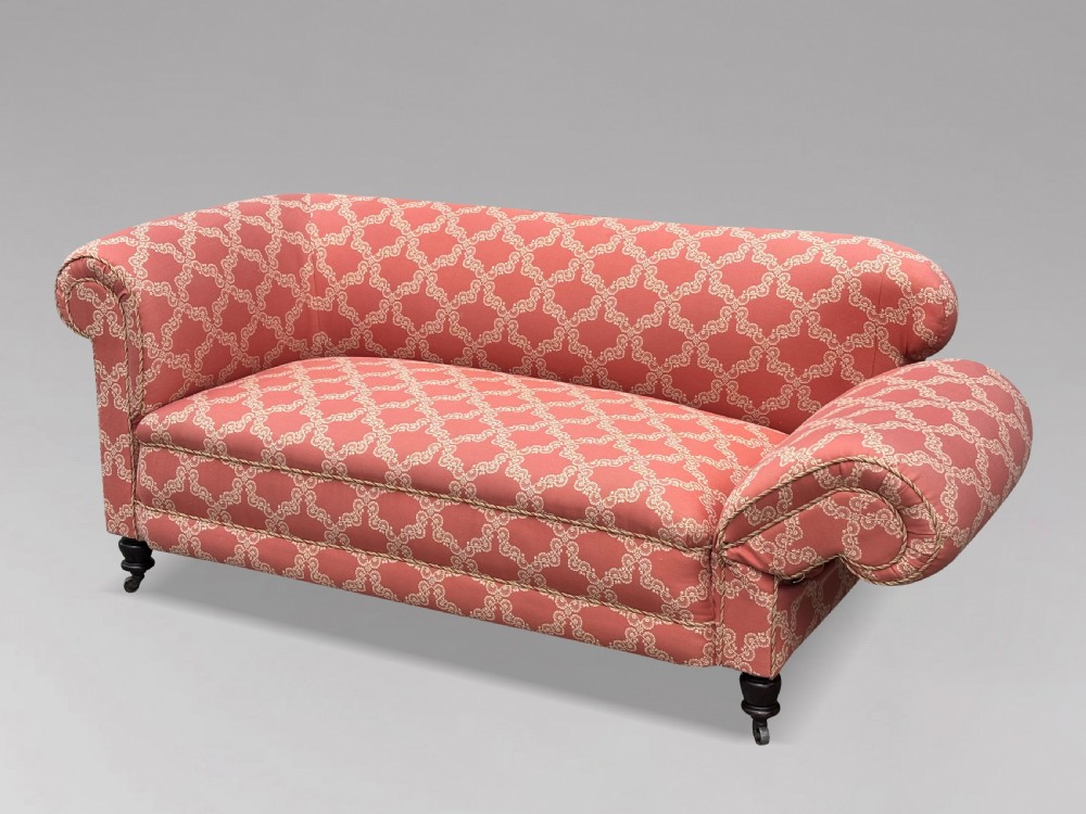 A 19th-century Victorian upholstered sofa featuring terracotta and cream patterned fabric, rolled arms, and dark turned wooden legs on brass castors. View II