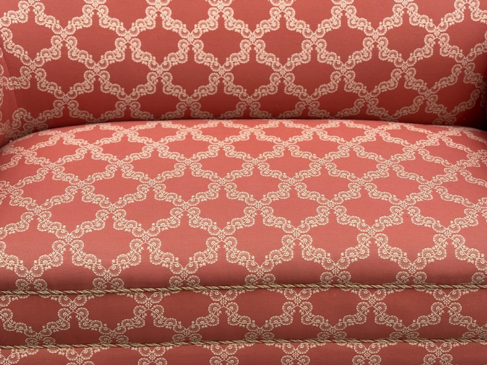 A 19th-century Victorian upholstered sofa featuring terracotta and cream patterned fabric, rolled arms, and dark turned wooden legs on brass castors. View III
