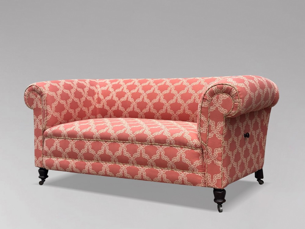 A 19th-century Victorian upholstered sofa featuring terracotta and cream patterned fabric, rolled arms, and dark turned wooden legs on brass castors. View IX