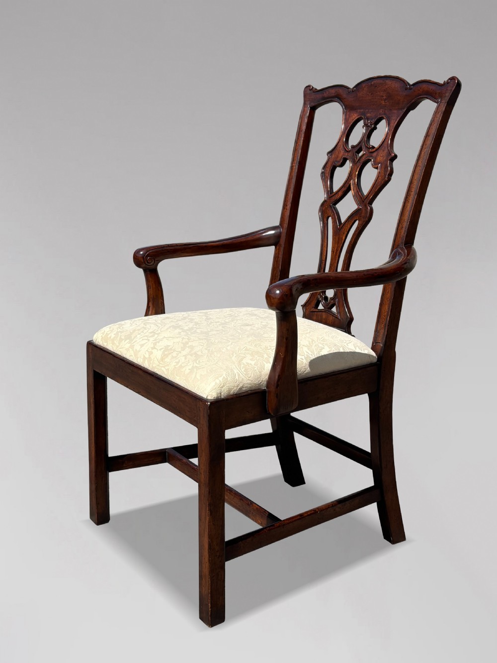 A set of six Edwardian mahogany dining chairs featuring pierced carved back splats, serpentine top rails, cream upholstered seats, and straight square legs with H-stretchers. View V