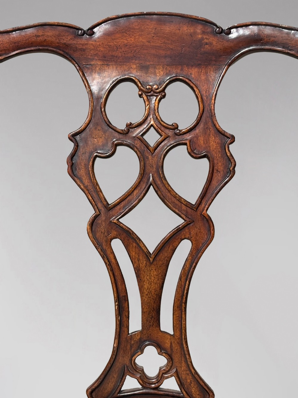 A set of six Edwardian mahogany dining chairs featuring pierced carved back splats, serpentine top rails, cream upholstered seats, and straight square legs with H-stretchers. View VI