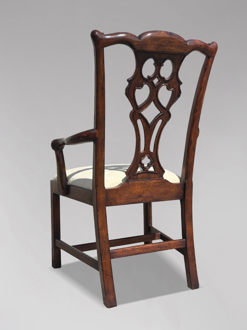 A set of six Edwardian mahogany dining chairs featuring pierced carved back splats, serpentine top rails, cream upholstered seats, and straight square legs with H-stretchers. View XI
