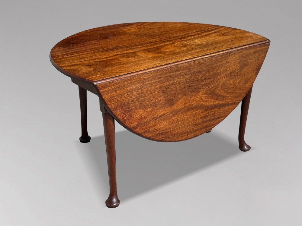 An 18th-century George II mahogany drop-leaf dining table with a round top and tapered legs ending in pad feet. View II