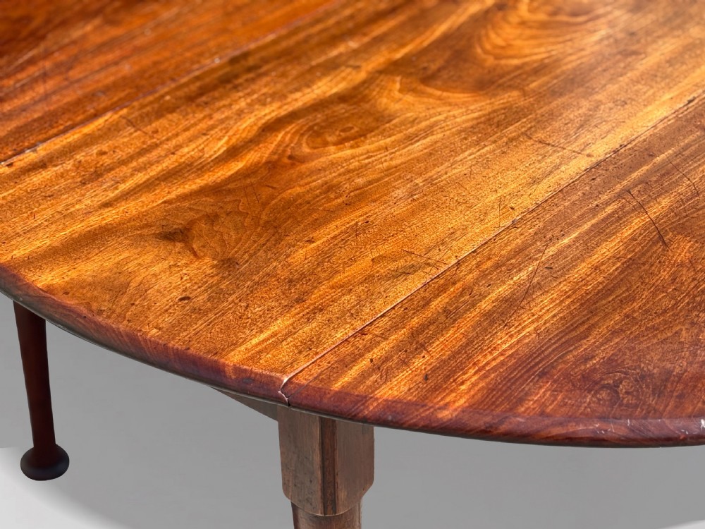 An 18th-century George II mahogany drop-leaf dining table with a round top and tapered legs ending in pad feet. View IV