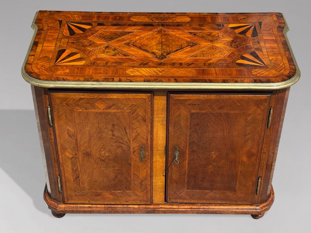 An 18th-century Maltese walnut cabinet with geometric parquetry inlays on the top and two panelled doors flanked by rounded corners on turned feet. View II