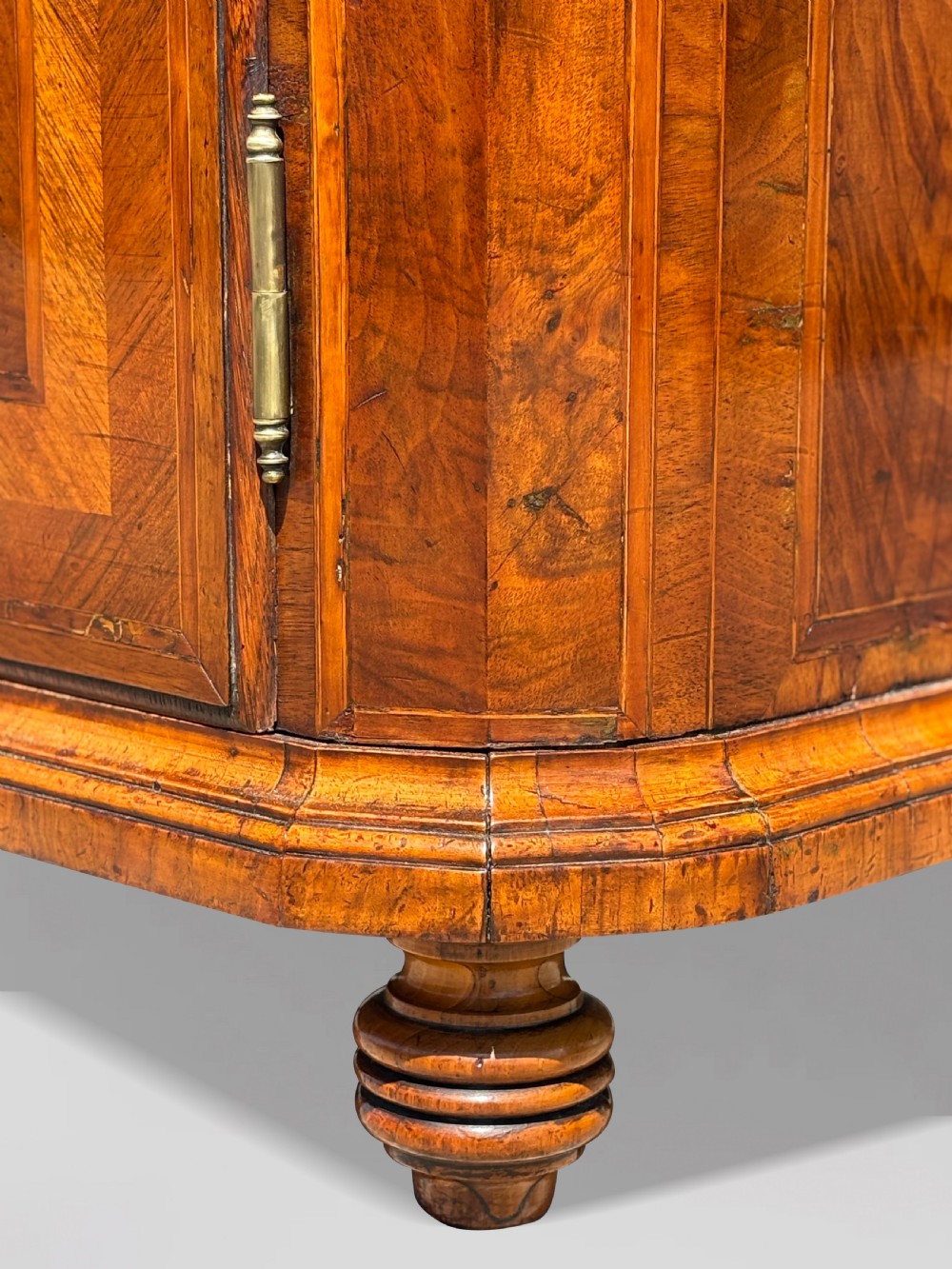 An 18th-century Maltese walnut cabinet with geometric parquetry inlays on the top and two panelled doors flanked by rounded corners on turned feet. View V