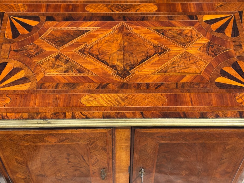 An 18th-century Maltese walnut cabinet with geometric parquetry inlays on the top and two panelled doors flanked by rounded corners on turned feet. View VI