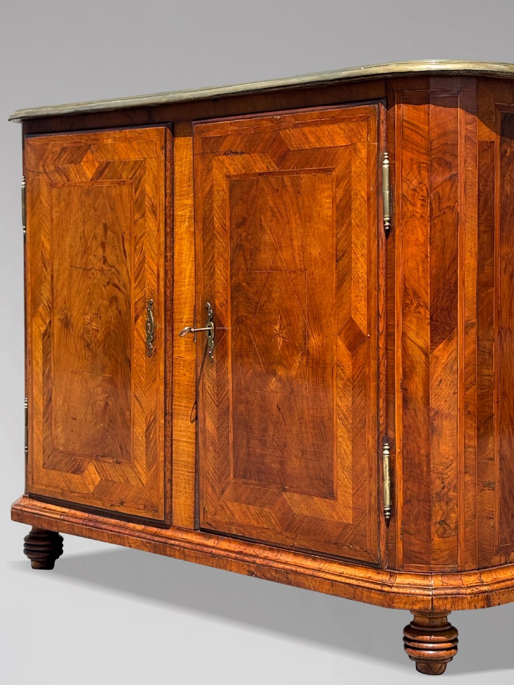 An 18th-century Maltese walnut cabinet with geometric parquetry inlays on the top and two panelled doors flanked by rounded corners on turned feet. View XI