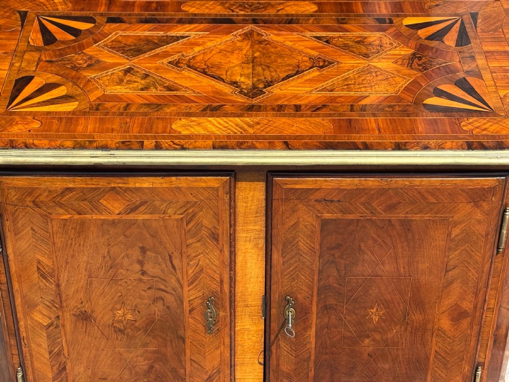 An 18th-century Maltese walnut cabinet with geometric parquetry inlays on the top and two panelled doors flanked by rounded corners on turned feet. View XIV