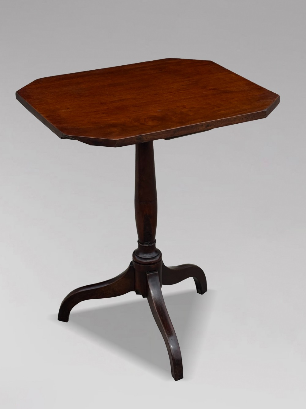An 18th-century George III dark mahogany tripod table featuring a turned central stem and a top with canted corners.