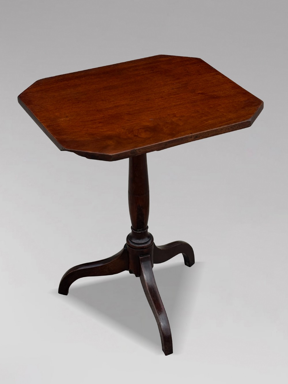An 18th-century George III dark mahogany tripod table featuring a turned central stem and a top with canted corners. View II