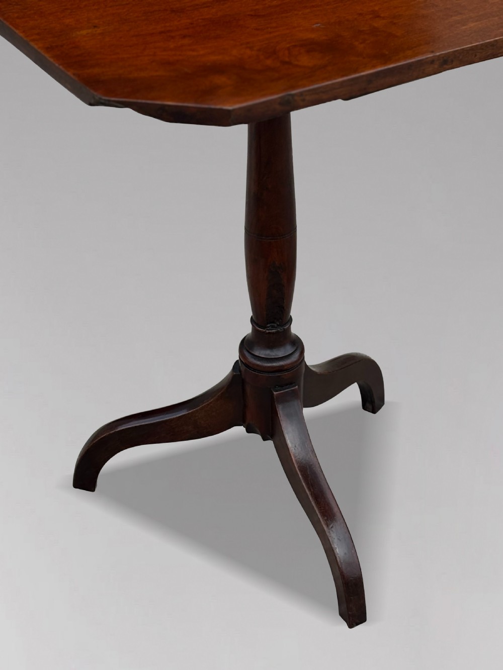 An 18th-century George III dark mahogany tripod table featuring a turned central stem and a top with canted corners. View III