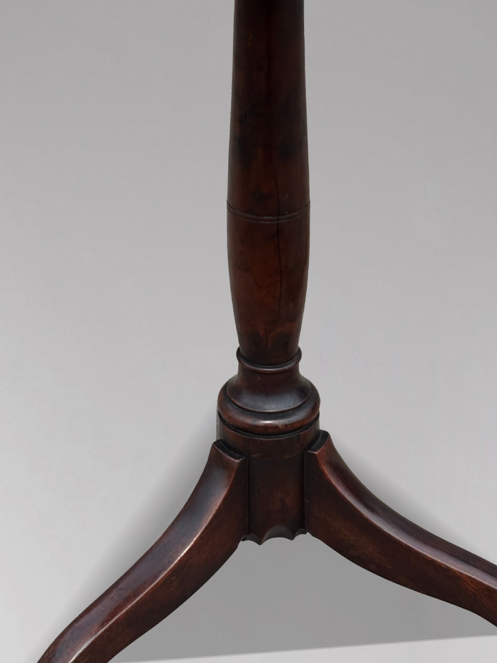 An 18th-century George III dark mahogany tripod table featuring a turned central stem and a top with canted corners. View IV