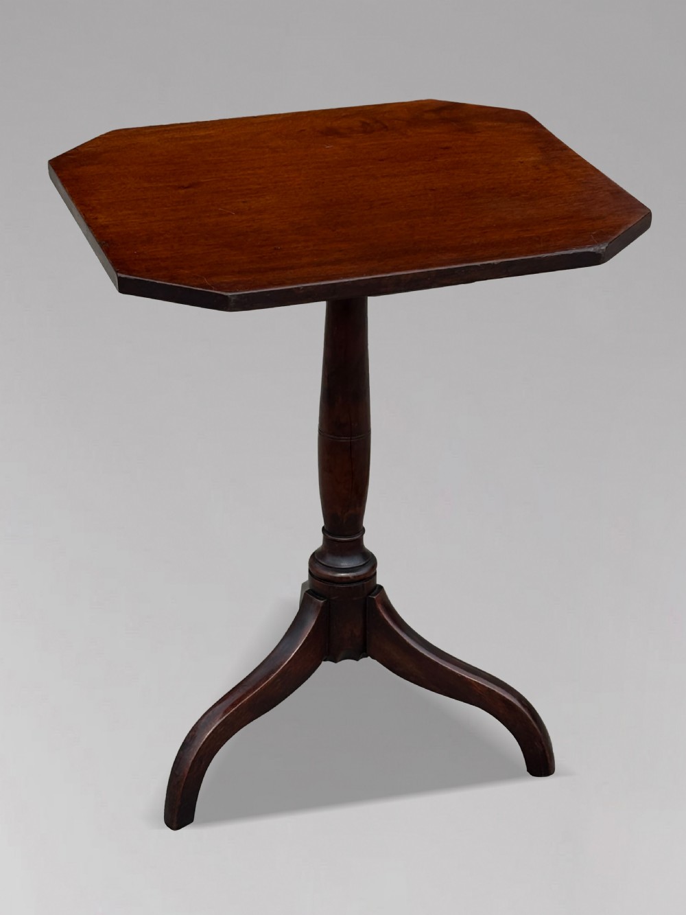 An 18th-century George III dark mahogany tripod table featuring a turned central stem and a top with canted corners. View VI