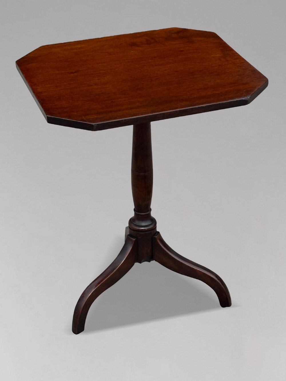 An 18th-century George III dark mahogany tripod table featuring a turned central stem and a top with canted corners. View VII