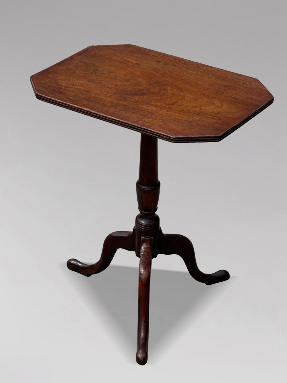 An 18th-century George III mahogany tripod table featuring an octagonal top, a central turned column, and three cabriole legs.