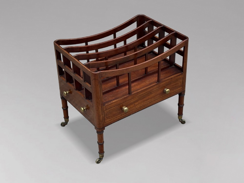 An 18th-century George III mahogany canterbury featuring slatted divisions, lower drawers with brass knobs, and turned legs on brass castors. View IX