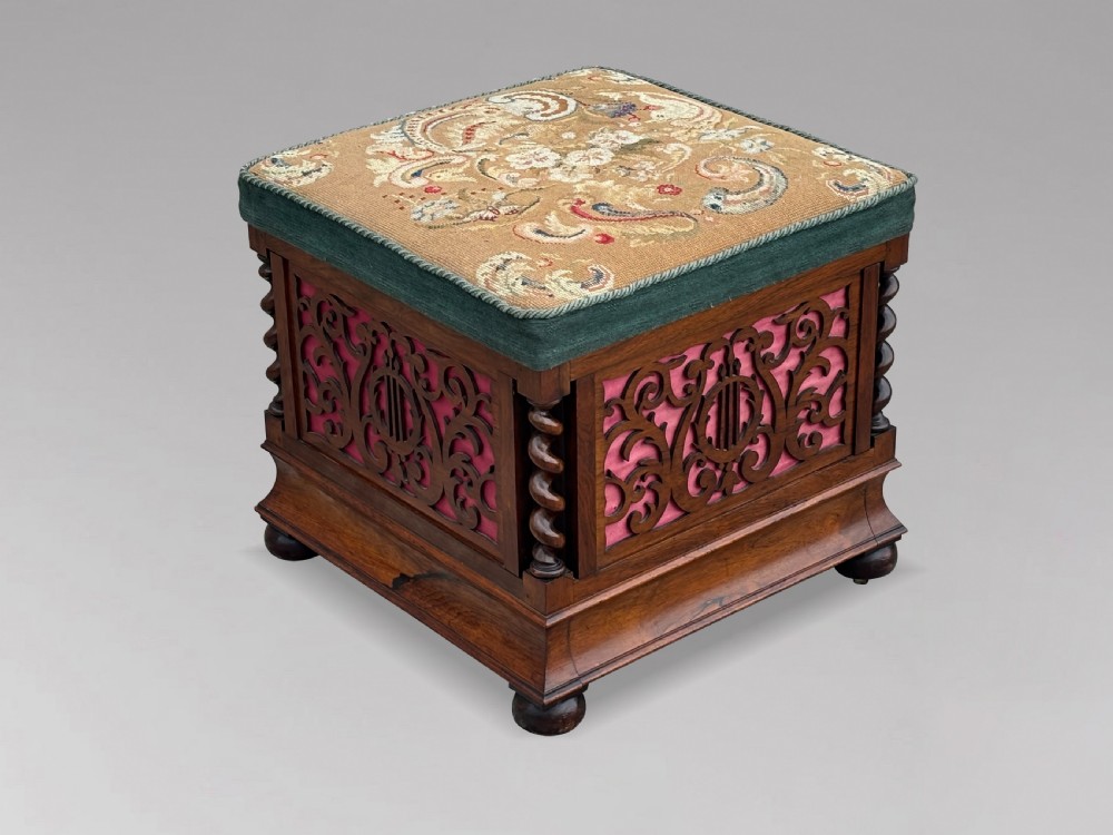A Victorian rosewood piano stool featuring a square tapestry-upholstered top with green velvet edging, carved fretwork side panels, corner barley twist columns, and bun feet. View III