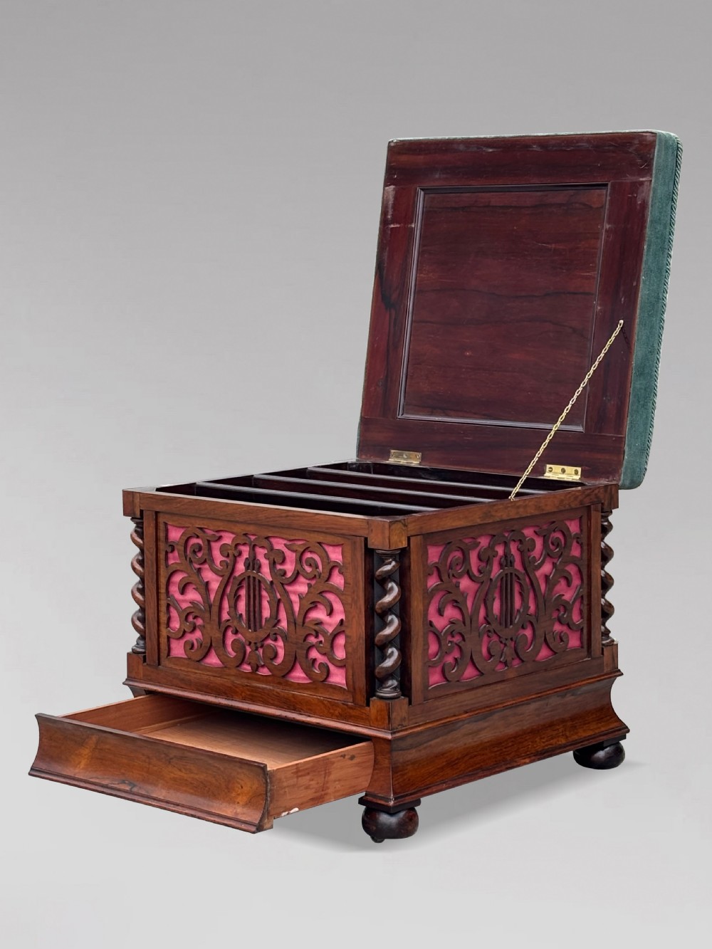 A Victorian rosewood piano stool featuring a square tapestry-upholstered top with green velvet edging, carved fretwork side panels, corner barley twist columns, and bun feet. View X