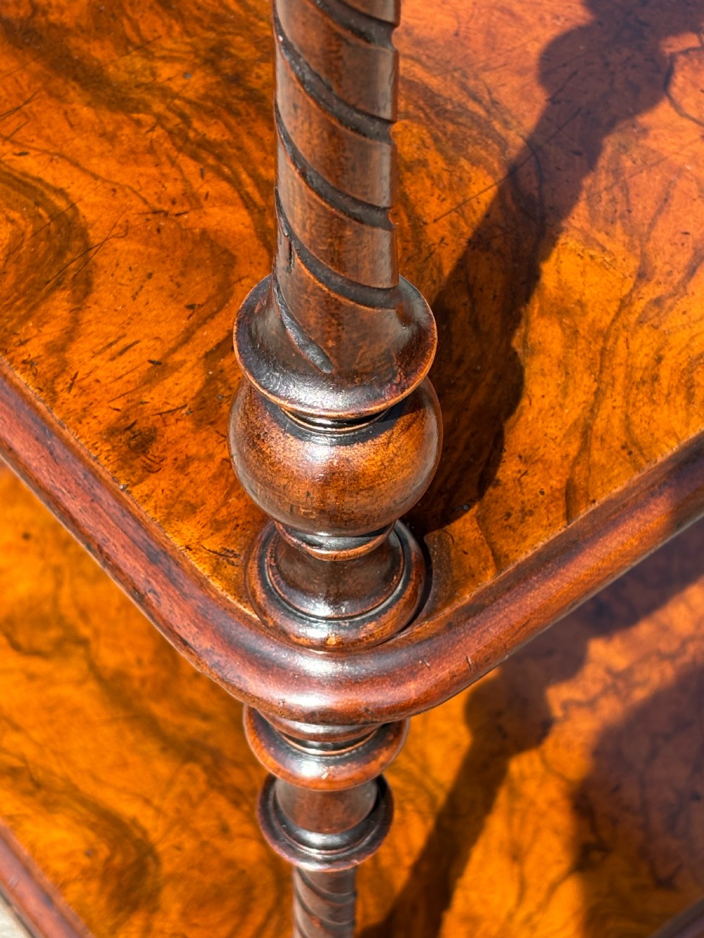 A Victorian walnut three-tier whatnot featuring barley twist supports, a single lower drawer, and brass castors. View III