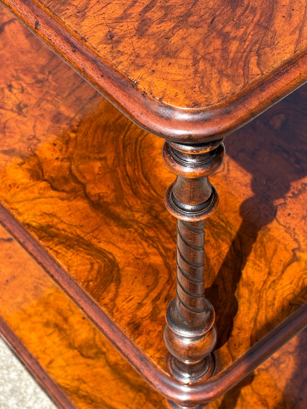 A Victorian walnut three-tier whatnot featuring barley twist supports, a single lower drawer, and brass castors. View VI