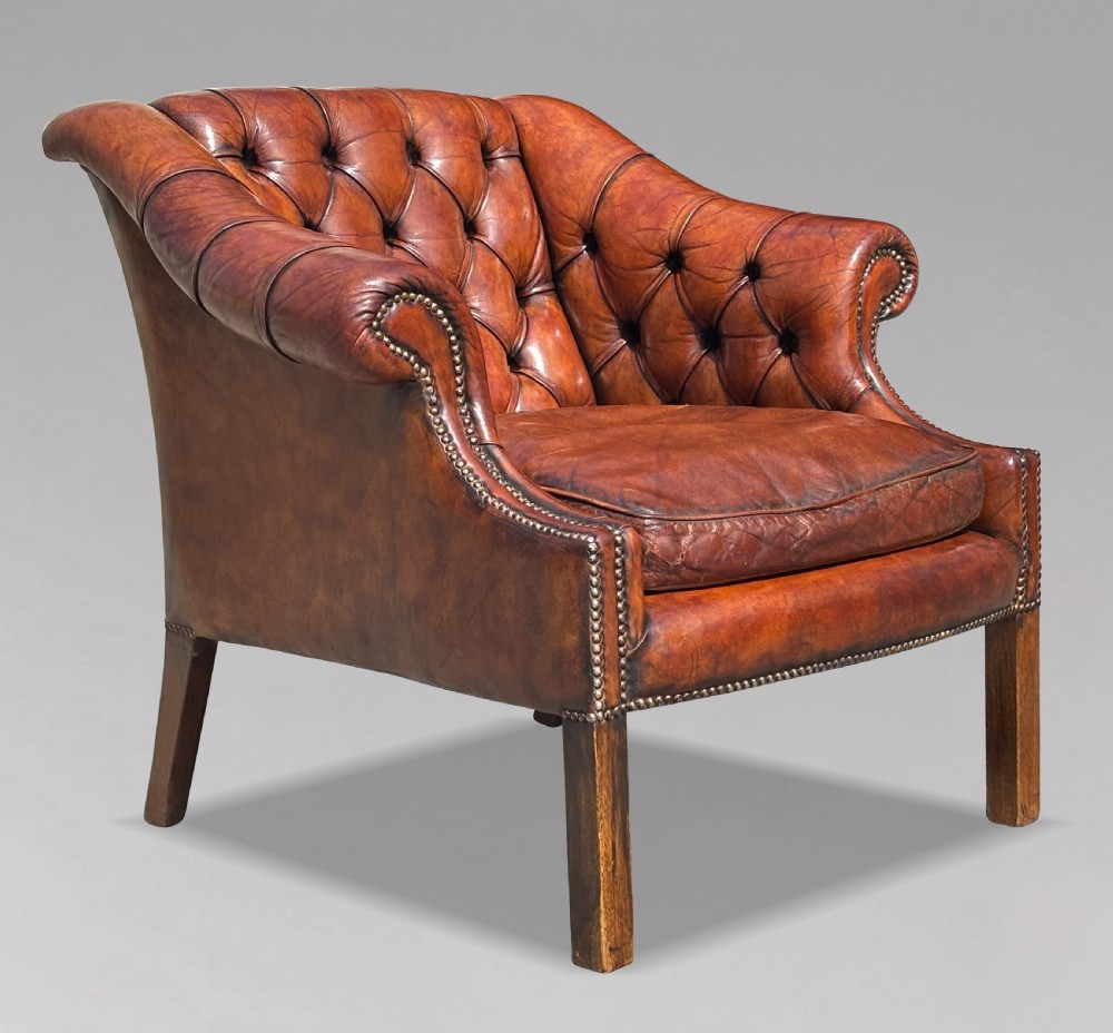 A nineteenth-century armchair upholstered in deep-buttoned brown leather with brass stud trimming along the arms and front rail, set on square wooden legs.