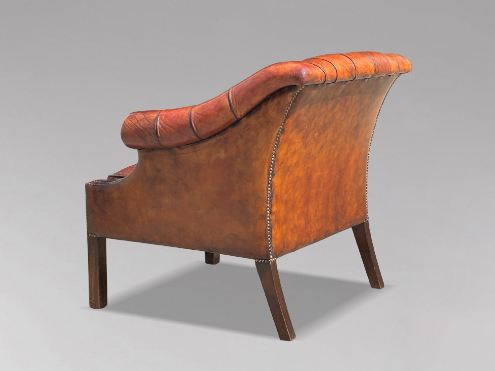 A nineteenth-century armchair upholstered in deep-buttoned brown leather with brass stud trimming along the arms and front rail, set on square wooden legs. View II