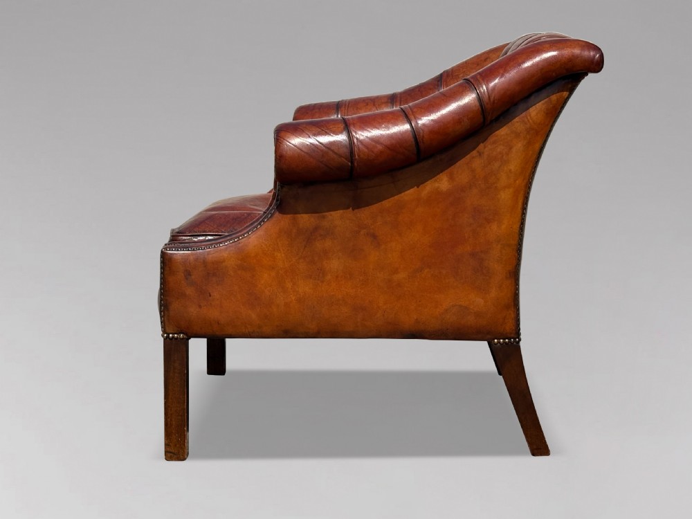 A nineteenth-century armchair upholstered in deep-buttoned brown leather with brass stud trimming along the arms and front rail, set on square wooden legs. View III