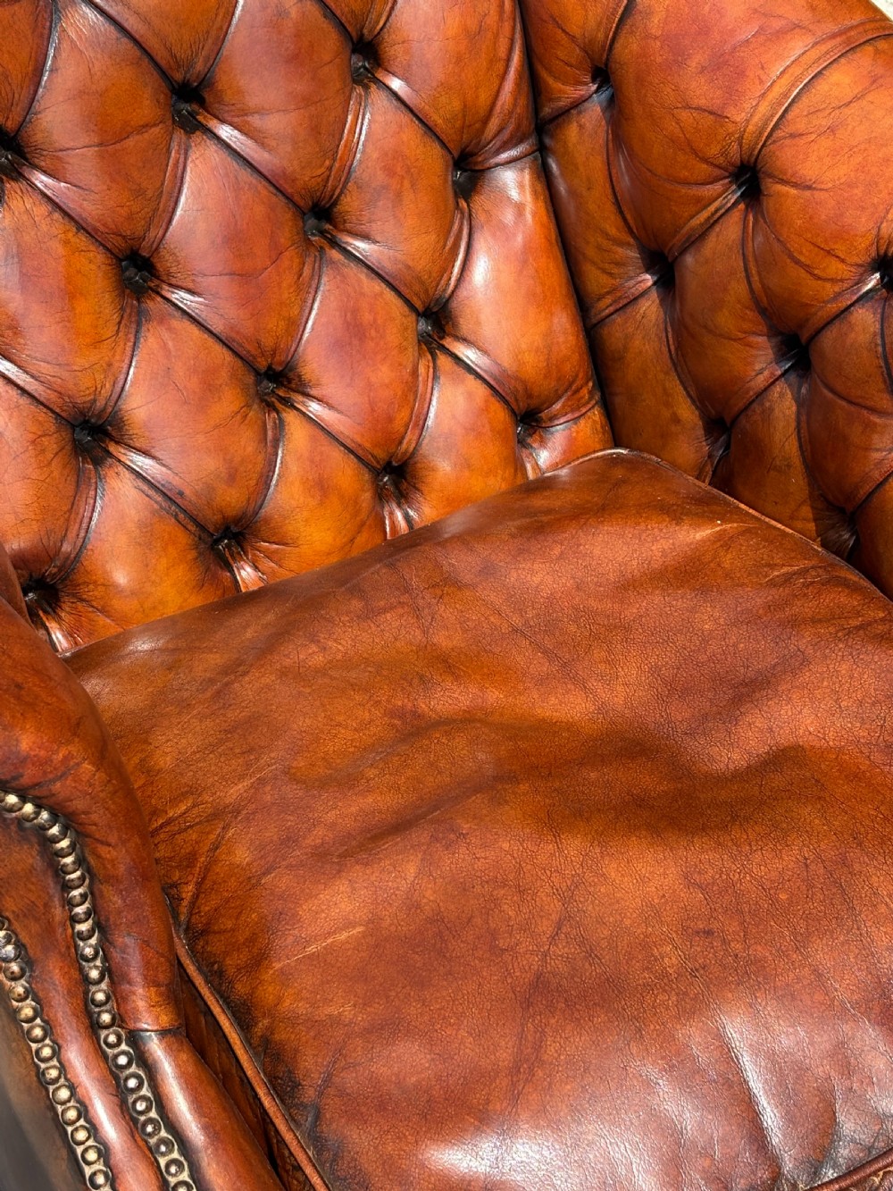 A nineteenth-century armchair upholstered in deep-buttoned brown leather with brass stud trimming along the arms and front rail, set on square wooden legs. View VII