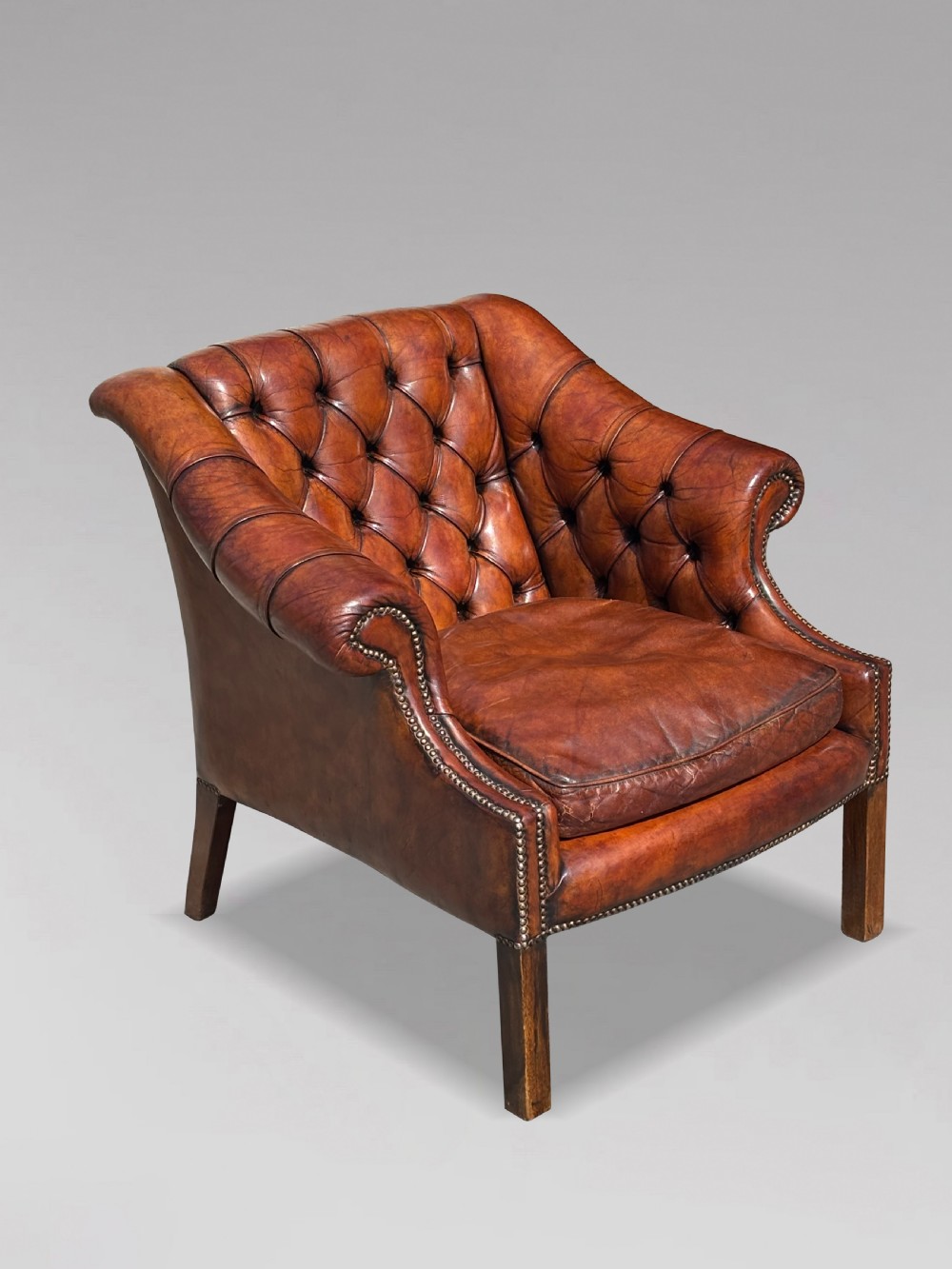 A nineteenth-century armchair upholstered in deep-buttoned brown leather with brass stud trimming along the arms and front rail, set on square wooden legs. View VIII