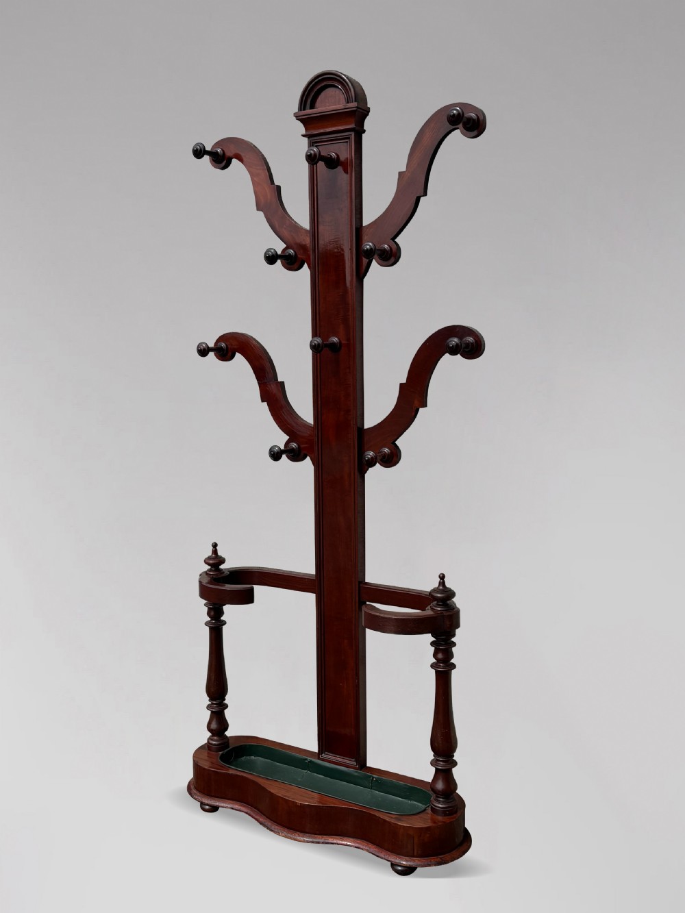A 19th-century Victorian mahogany hall stand with carved coat pegs, turned supports, and an umbrella base featuring a green drip tray. View II