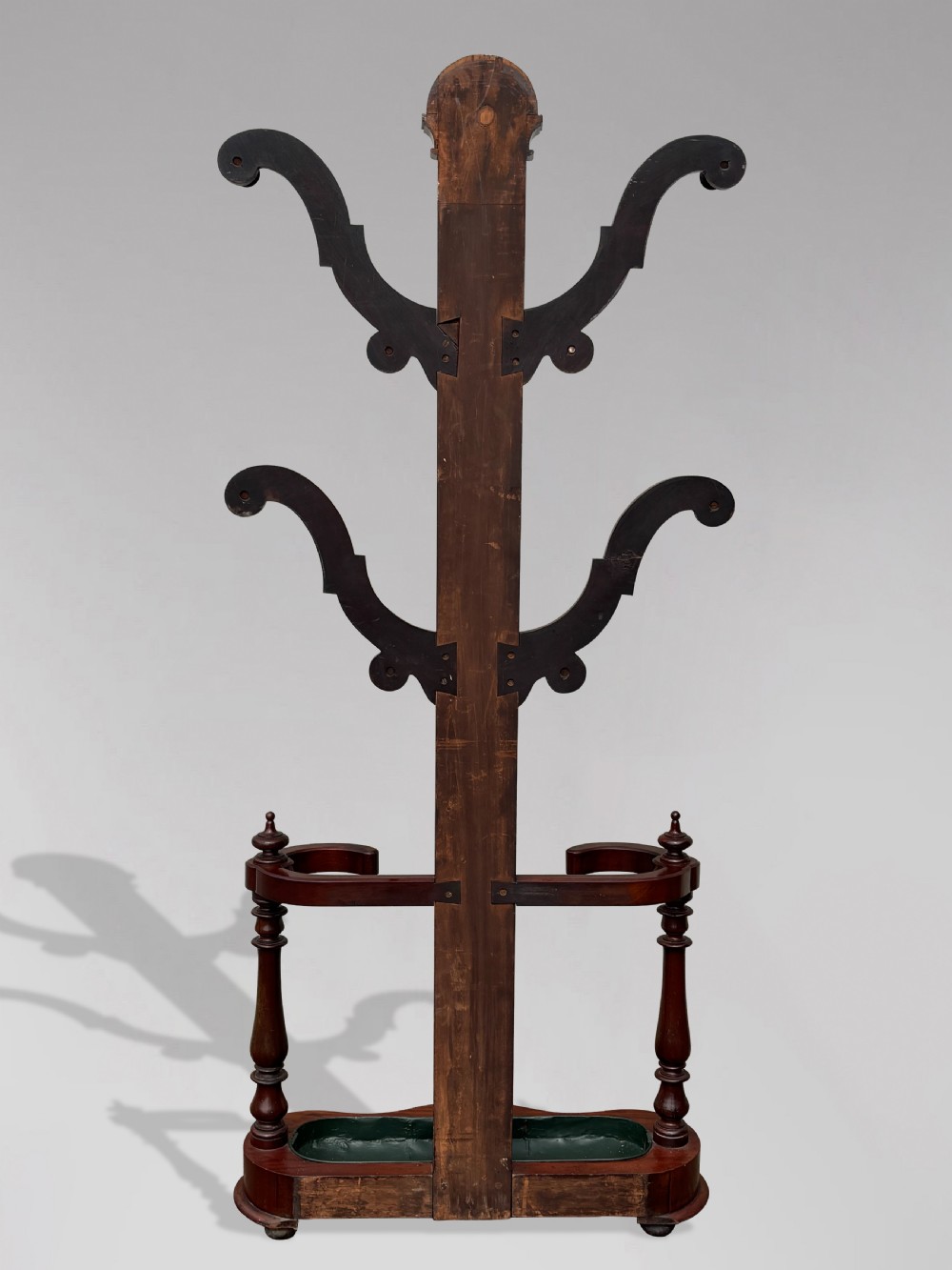 A 19th-century Victorian mahogany hall stand with carved coat pegs, turned supports, and an umbrella base featuring a green drip tray. View VI