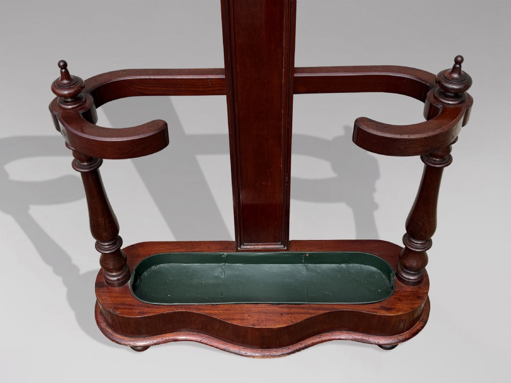A 19th-century Victorian mahogany hall stand with carved coat pegs, turned supports, and an umbrella base featuring a green drip tray. View VIII