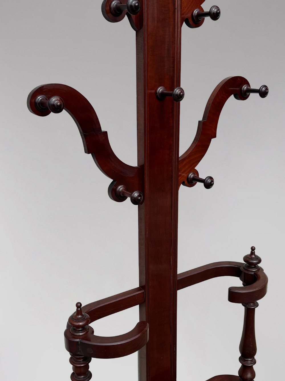 A 19th-century Victorian mahogany hall stand with carved coat pegs, turned supports, and an umbrella base featuring a green drip tray. View X