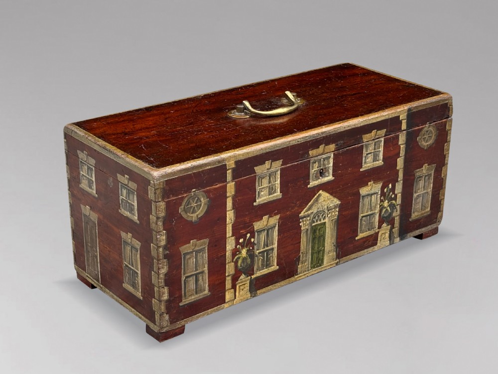 A rectangular dark red painted oak box decorated with a detailed Georgian house facade, featuring a brass handle on the top lid. View II