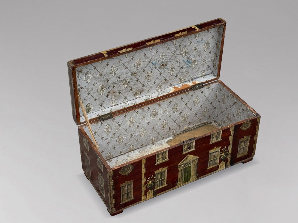 A rectangular dark red painted oak box decorated with a detailed Georgian house facade, featuring a brass handle on the top lid. View IV