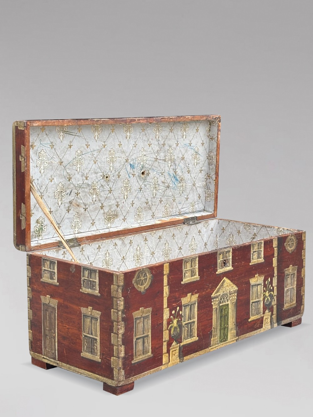 A rectangular dark red painted oak box decorated with a detailed Georgian house facade, featuring a brass handle on the top lid. View VII