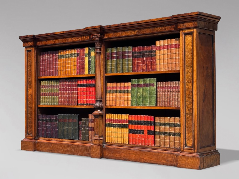 A low 19th-century William IV open bookcase crafted from burr walnut with two shelf sections flanked by carved pilasters.