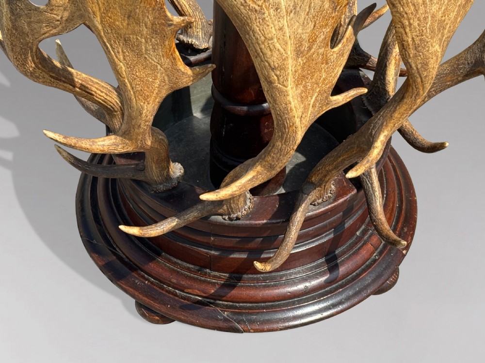 A Victorian freestanding coat stand crafted with a central barley-twist dark wood shaft surrounded by shed fallow deer antlers on a turned circular base. View VIII