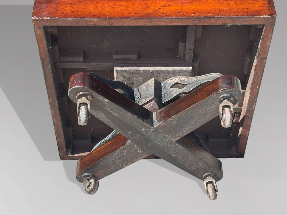 A late 19th-century Victorian mahogany revolving bookcase featuring three tiers of open shelving with vertical side slats and a square top, resting on castors. View III