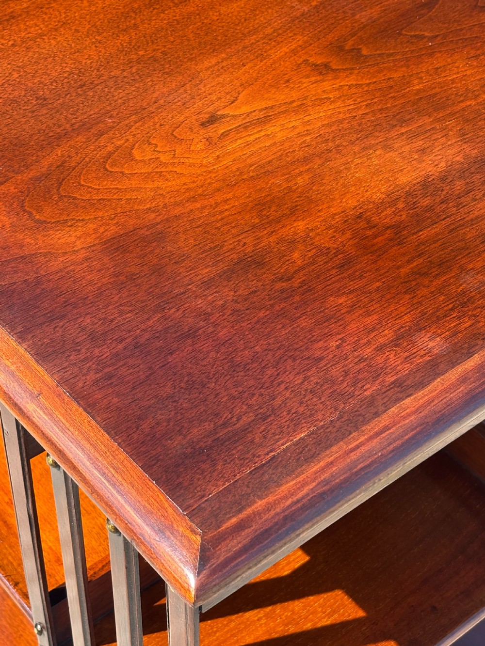 A late 19th-century Victorian mahogany revolving bookcase featuring three tiers of open shelving with vertical side slats and a square top, resting on castors. View VI