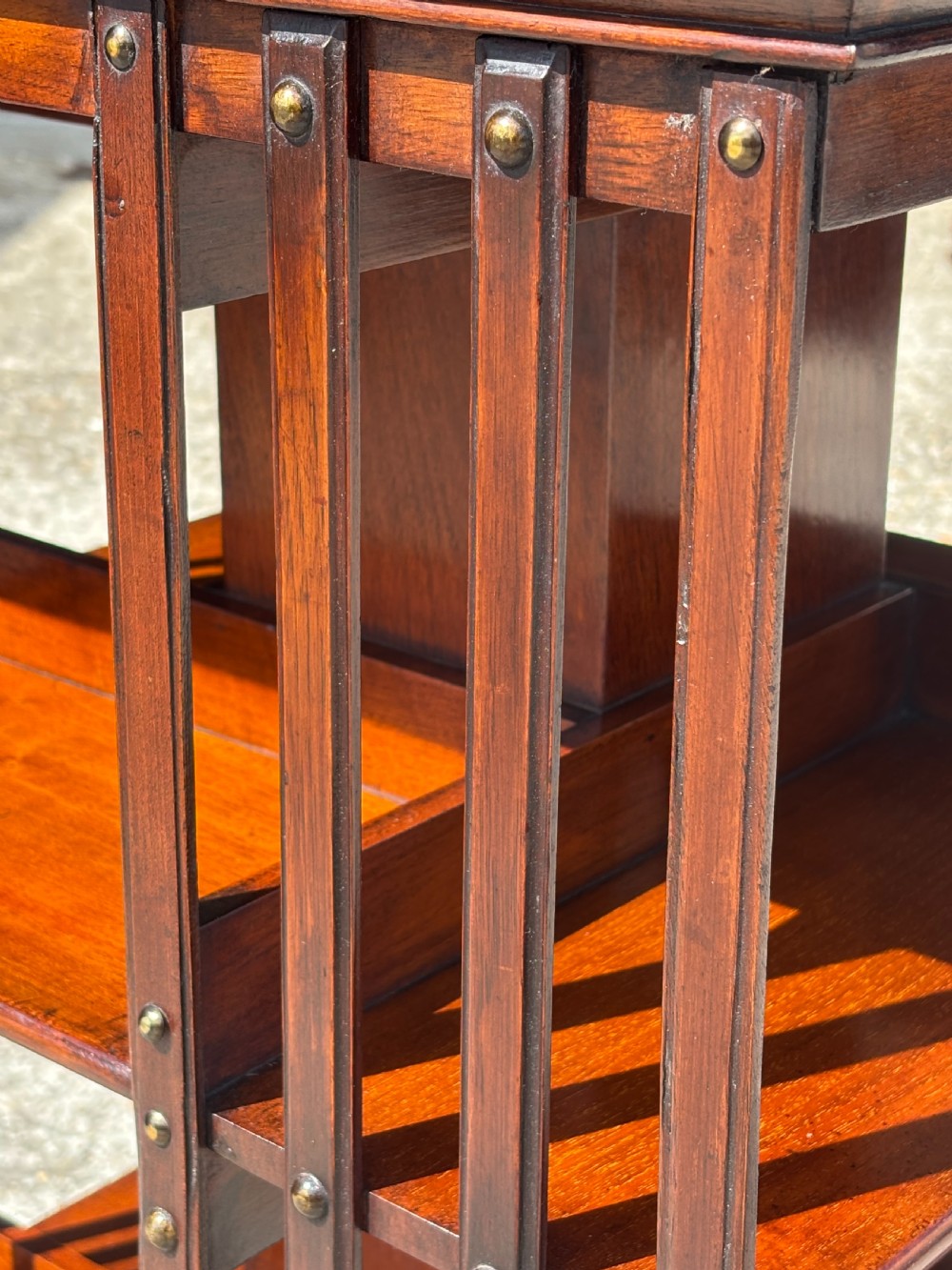 A late 19th-century Victorian mahogany revolving bookcase featuring three tiers of open shelving with vertical side slats and a square top, resting on castors. View VII