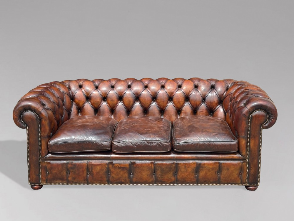 A nineteenth-century three-seater Chesterfield sofa upholstered in deep buttoned chestnut brown leather with brass stud detailing along the rolled arms. View III